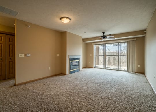 a large living room with a two-way fireplace, a ceiling fan, and a large sliding glass door for plenty of natural light