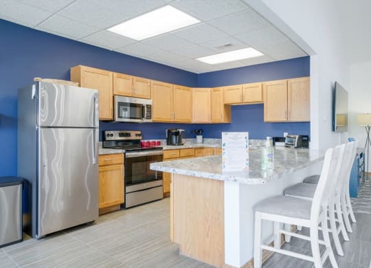 Community kitchen with stainless steel appliances, blue accent wall, and a counter with chairs for dining