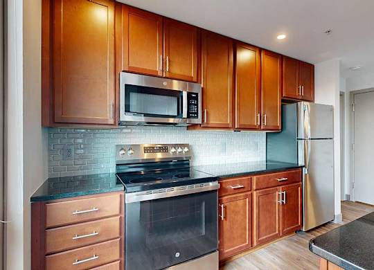 a modern kitchen with brown wooden cabinets, stainless steel appliances, black granite countertops, and a tile backsplash