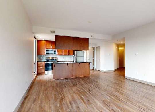 a kitchen and living room with wooden floors and white walls