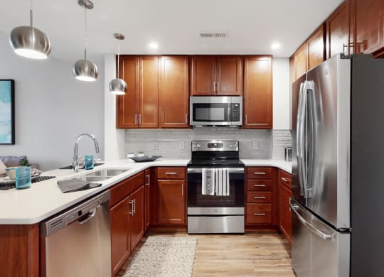 Spacious kitchen with peninsula and quartz or granite counter top and tile back splash in a 1 bedroom floor plan at Midtown Crossing Apartments Omaha