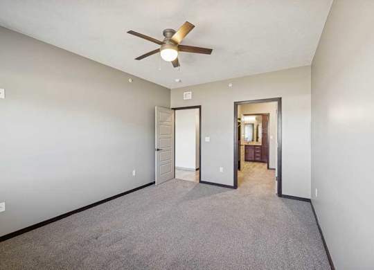 A room with a ceiling fan and carpeted floor.