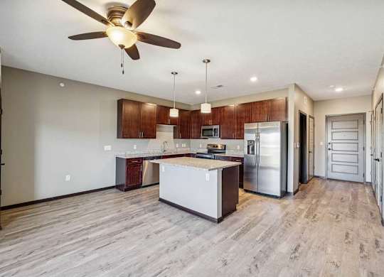 A modern kitchen with a wooden floor and a ceiling fan.