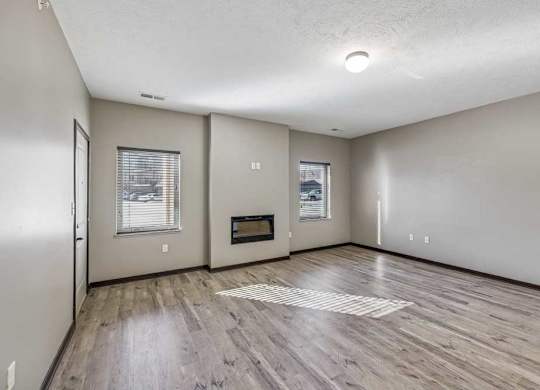 A spacious room with a wood floor and a window.