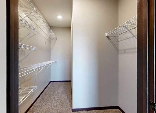 A long walk-in closet with built-in shelves along the left, and additional hanging space on the right.