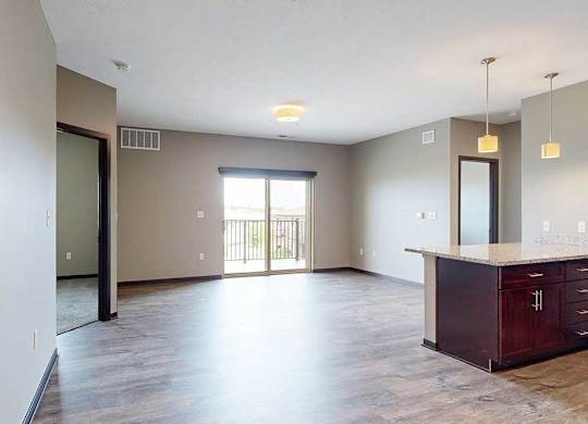 A spacious living area with neutral walls and wood-style flooring.