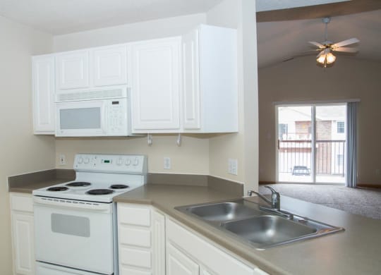 an empty kitchen with white appliances and a sink