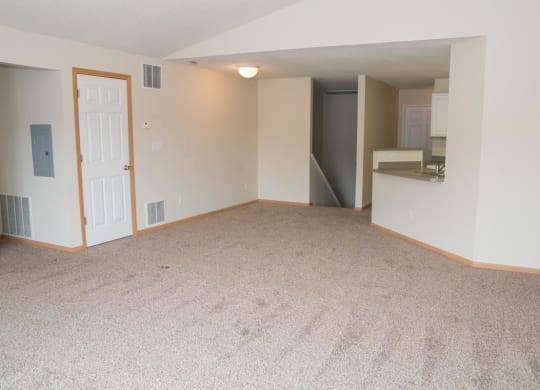 an empty living room with a door to the kitchen