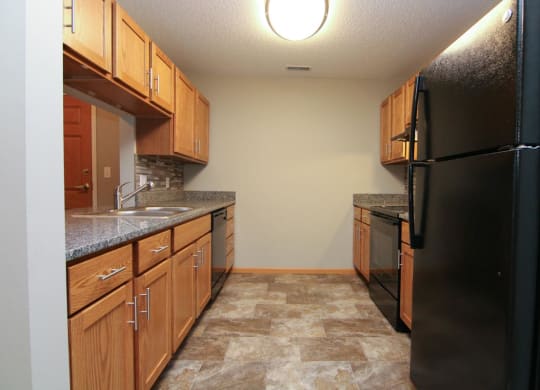 a kitchen with wooden cabinets and a black refrigerator