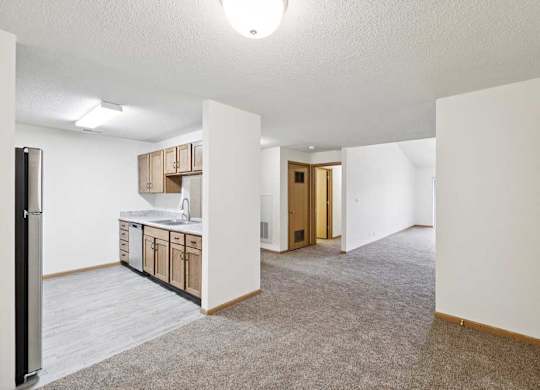 A kitchen area with a sink, cabinets, and a refrigerator.