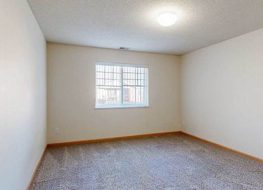 Empty room with a window and a carpeted floor.