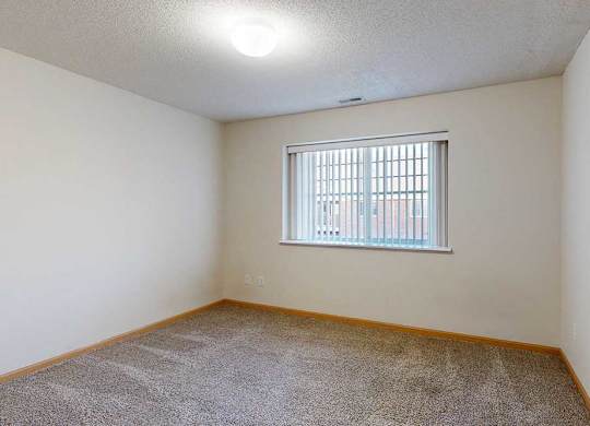 A room with a window and carpeted floor.