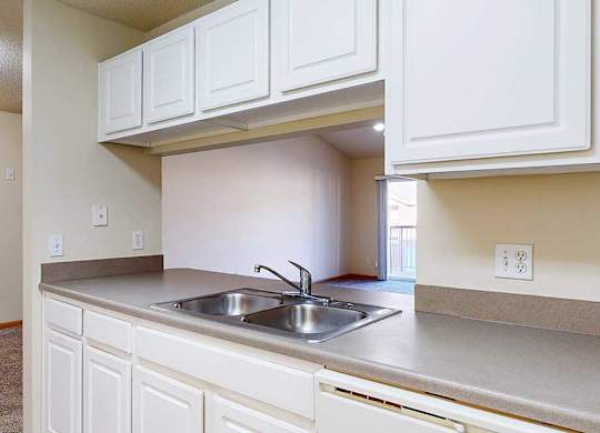 A kitchen with white cabinets and a stainless steel sink.