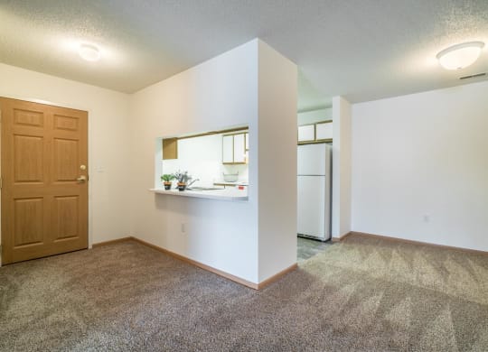 an empty living room with a refrigerator and a door