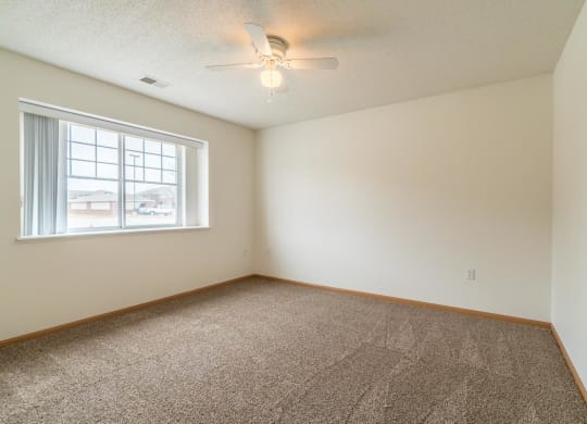 an empty room with a window and a ceiling fan