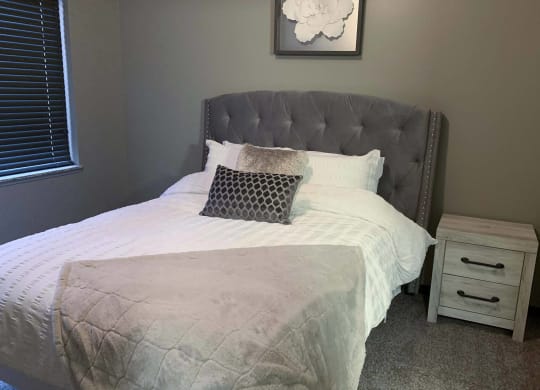 a bed with a white comforter and pillows in a small bedroom