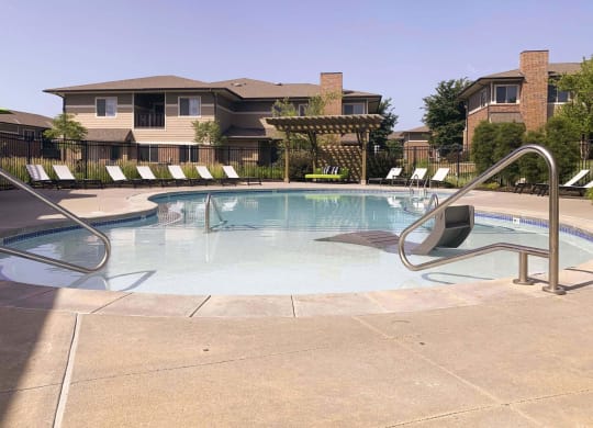 a swimming pool with chairs around it and a building in the background