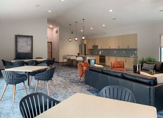 a large community room with tables and chairs and a kitchen