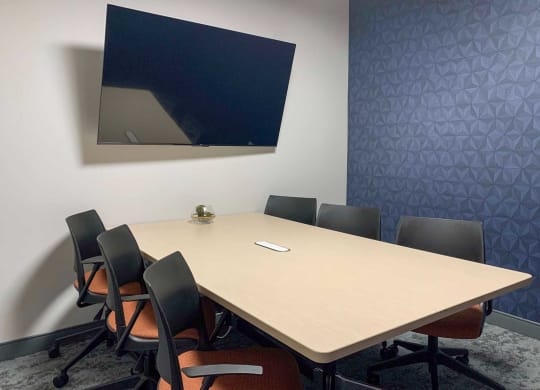 a clubhouse conference room with a table and chairs and a tv