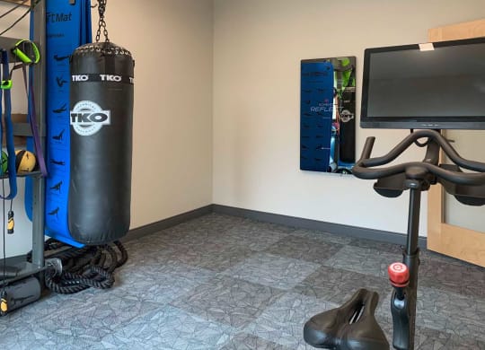 a corner of a gyp with punching bag, fitness mirror, and spin bike