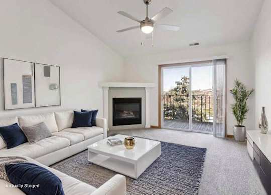 A living room with a white couch, a fireplace, and a ceiling fan.