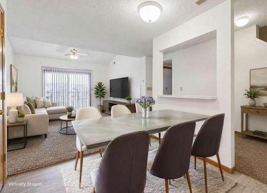 Open-concept apartment dining and living area with modern kitchen, white cabinetry, wood-style flooring, and breakfast bar seating.