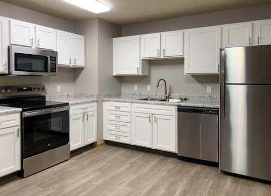 a kitchen with white cabinets, stainless appliances, and hardwood floors