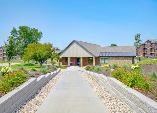 Walkway leading to a clubhouse with trees and landscaping