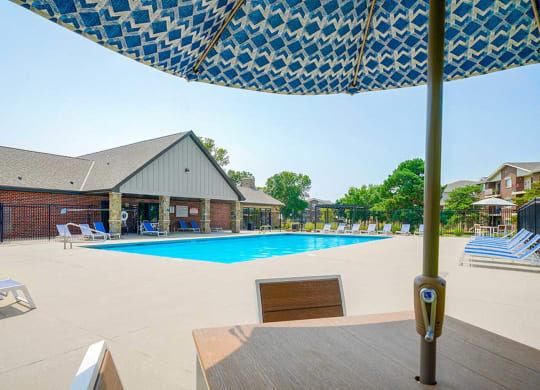 Swimming pool with an umbrella-covered table and chairs in the foreground