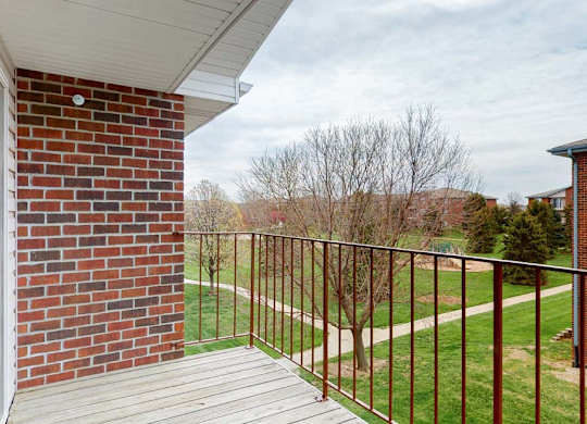 A balcony with a brick wall and a metal railing.