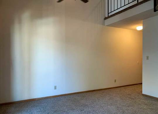 a living room with a vaulted ceiling, ceiling fan, and a loft area above