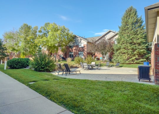 a courtyard patio with lounge chairs and a fire pit next to a little pond