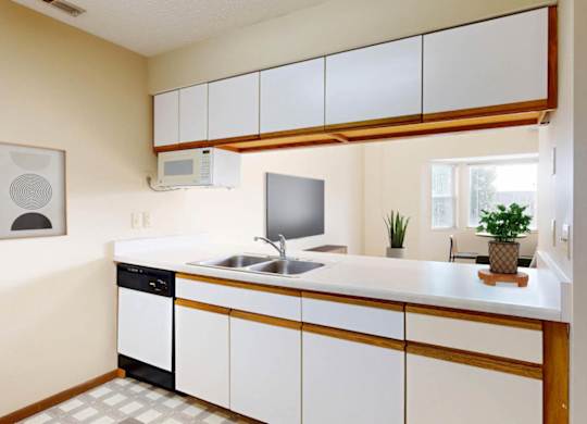 A kitchen with a white counter, white cabinets, and a pass through to the living room.