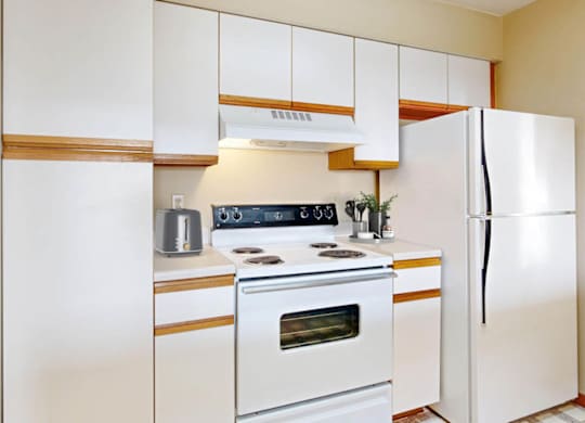 A white kitchen with a stove, oven, and refrigerator.