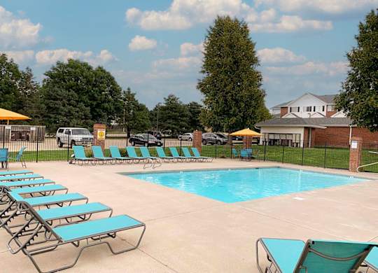A pool with sun loungers and a building in the background.
