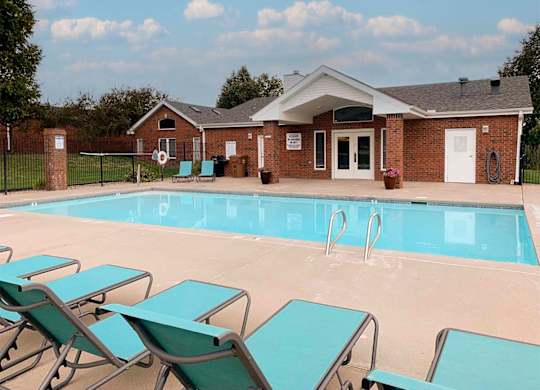 A pool with loungers in front of a building.