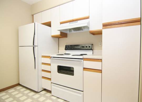 A white kitchen with a refrigerator, oven, and stove.