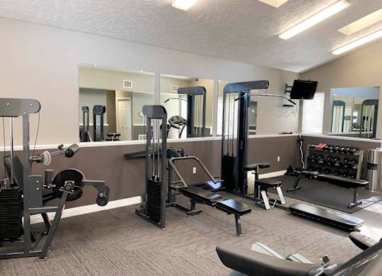 a gym with equipment and mirrors in apartment clubhouse