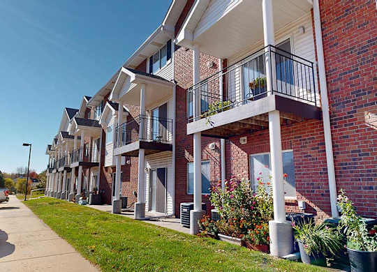 a red brick apartment building with white pillars and balconies with black metal railings