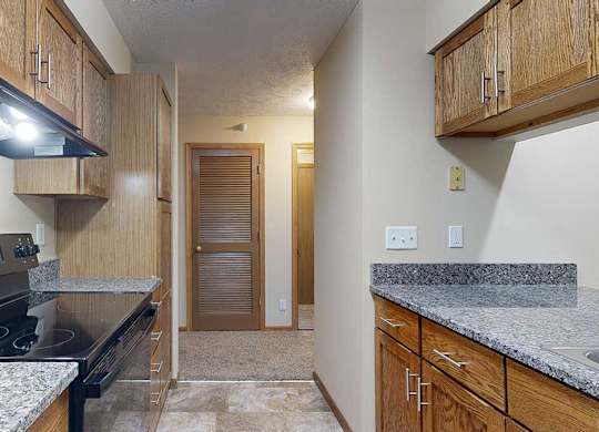 a galley kitchen with granite countertops and wooden cabinets