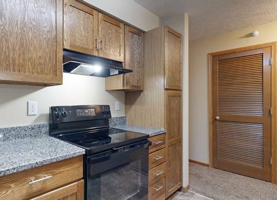 a kitchen featuring wooden cabinets, granite countertops, and black appliances