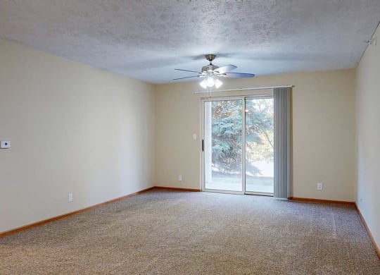 a living room with carpet, a ceiling fan, and a sliding glass door to a patio