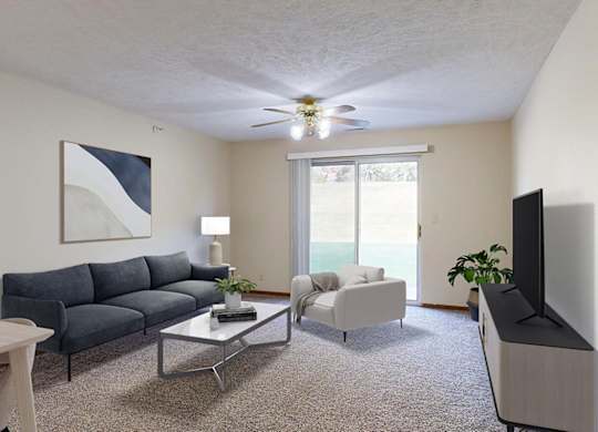 An apartment living room with a navy sofa, a white armchair, a glass coffee table, and a television.