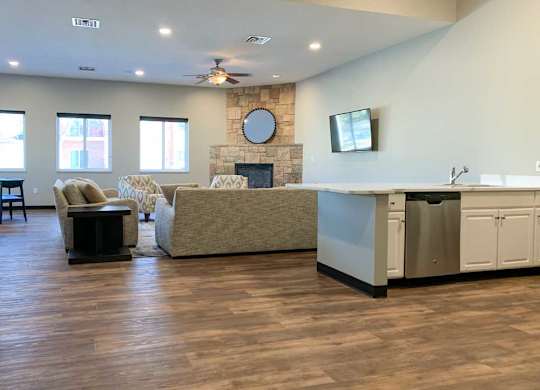 a tv lounge with a stone fire place and a grey couch, with hardwood flooring