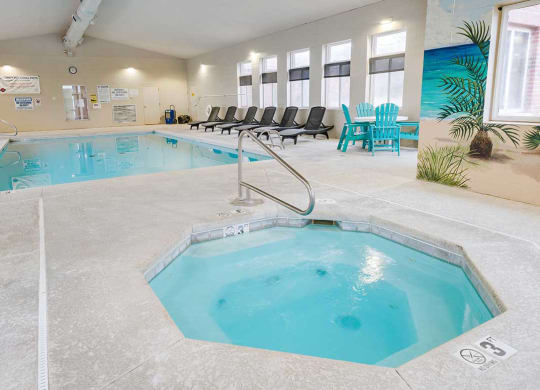 an indoor pool and hot tub with lounge chairs chairs