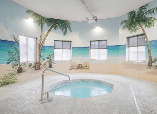 an indoor hot tub with a beach mural on the wall behind it