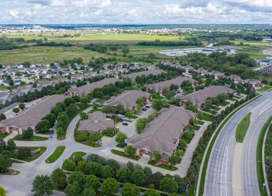 an aerial view of apartment community with multiple buildings, houses and cars