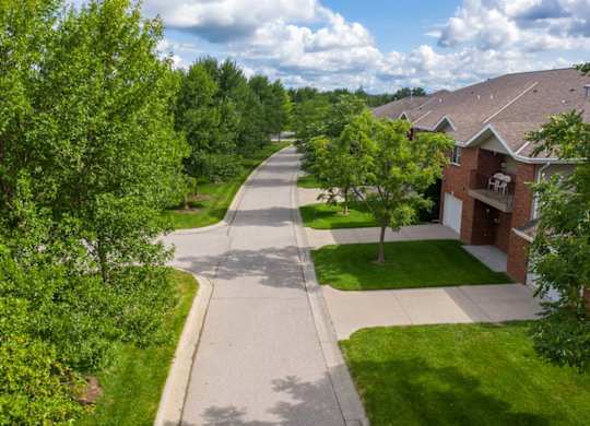 A residential street with houses on both sides and trees lining the road.