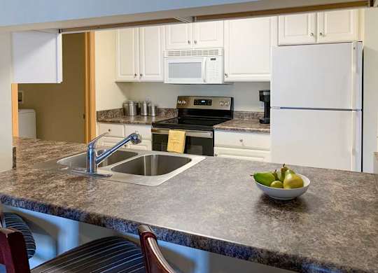 a kitchen with a bar top style counter, a sink, stove, and refrigerator