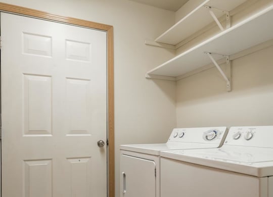 A white laundry room with a door and a washer and dryer.